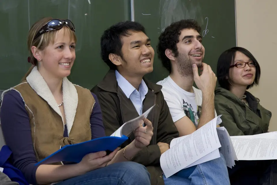 Quatre élèves en cours à l’École polytechnique, documents ouverts devant eux.